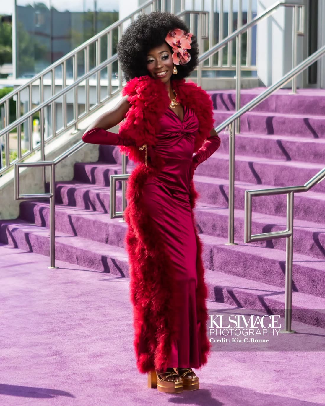 Gown with red feather trim, photographed on a purple-carpeted staircase